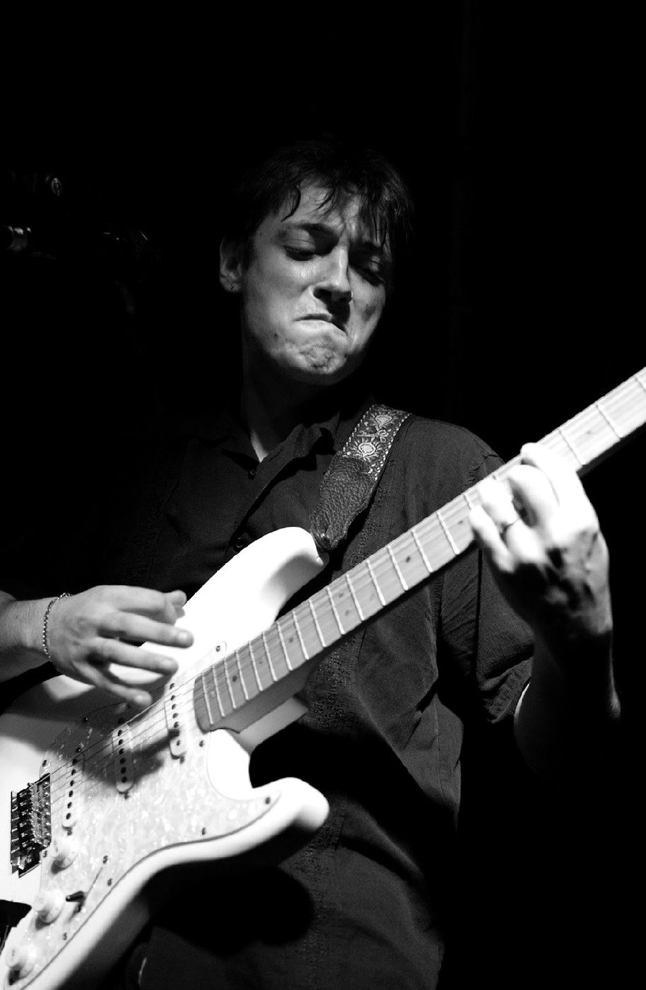 Nick Benak playing electric guitar on stage